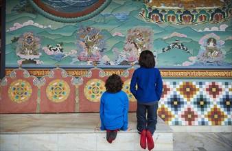 Mixed Race brothers kneeling on bench examining wall paintings