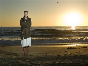 Caucasian woman standing on beach at sunset