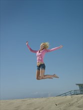 Caucasian woman jumping on beach