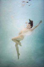 Pregnant Caucasian woman swimming underwater