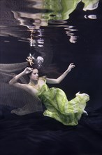 Mixed race woman in dress swimming under water