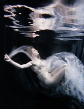 Caucasian woman in scarf swimming under water