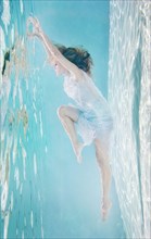 Mixed race woman in dress underwater in swimming pool
