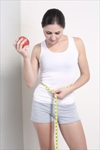 Caucasian woman holding apple measuring waist