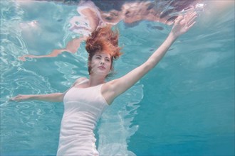 Underwater view of mixed race woman in dress swimming in pool