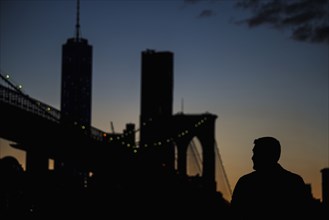 Silhouette of man admiring bridge at night