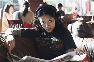 Filipino woman listening to headphones in coffee shop