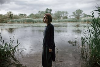Caucasian woman standing near river in rain
