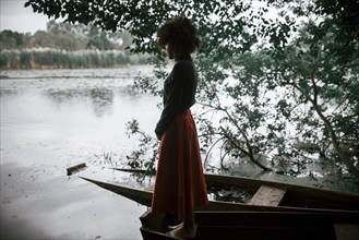 Caucasian woman standing in boat at river