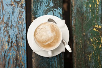 Cup of coffee with foam on wooden table