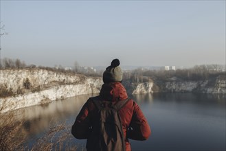 Caucasian man at the edge of reservoir wearing backpack
