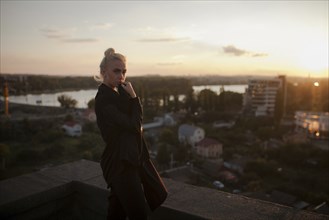 Pensive Caucasian woman standing on roof at sunset