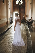 Caucasian woman wearing a wedding dress in hallway