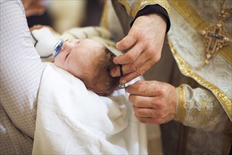 Priest clipping hair of baby girl