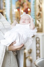 Priest holding baby girl in church
