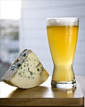 Glass of beer with wedge of cheese