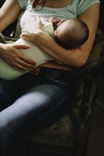 Mother breast-feeding baby in chair