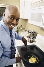 African man cooking eggs in kitchen