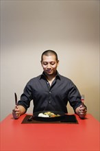 Asian man at table with full plate of food