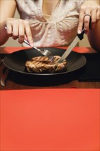 Close up of woman cutting meat on plate