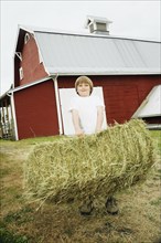 Boy holding bale of hay
