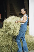 Girl stacking bales of hay