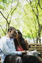 African couple hugging on bench