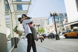 African hugging on sidewalk