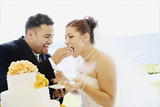 Multi-ethnic bride and groom eating cake