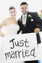 Multi-ethnic bride and groom holding sign