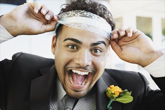 Hispanic groom wearing garter on head