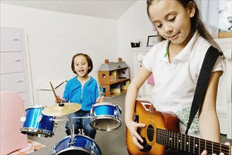 Asian sisters playing drums and guitar