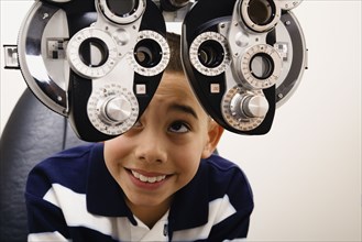Asian boy looking at eye examination equipment