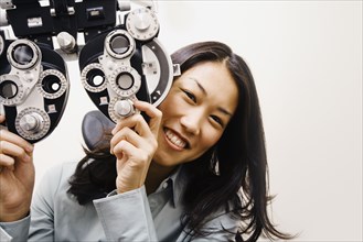 Asian woman next to ophthalmic refractor
