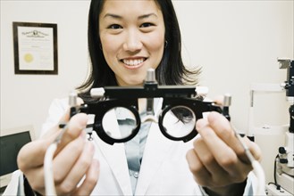 Asian female optometrist holding equipment