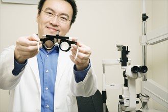 Asian male optometrist holding equipment