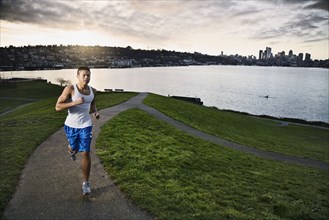 Asian man jogging along urban waterfront