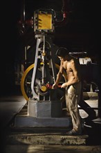 Bare chested Asian man working in factory