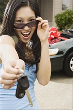 Asian teenager holding keys to new car