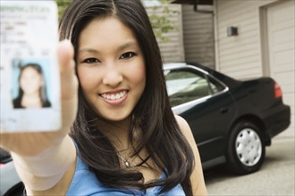 Asian teenager proudly showing new driver's license