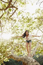 Hispanic woman standing on tree branch