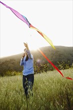 Asian woman flying kite in field