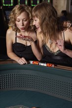 Woman blowing on dice for good luck in a casino