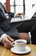 Businessman reaching for cup of coffee