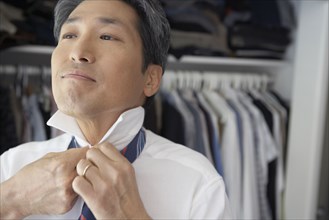 Asian businessman putting on tie