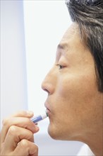Asian man applying lip balm