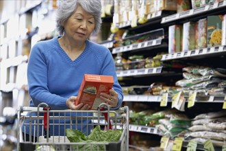 Senior Asian woman reading label at grocery store
