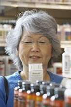 Senior Asian woman reading vitamin label