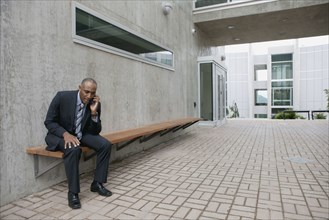 Mixed race businessman talking on cell phone in courtyard
