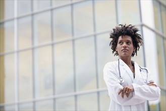 Mixed race doctor standing outdoors with arms crossed